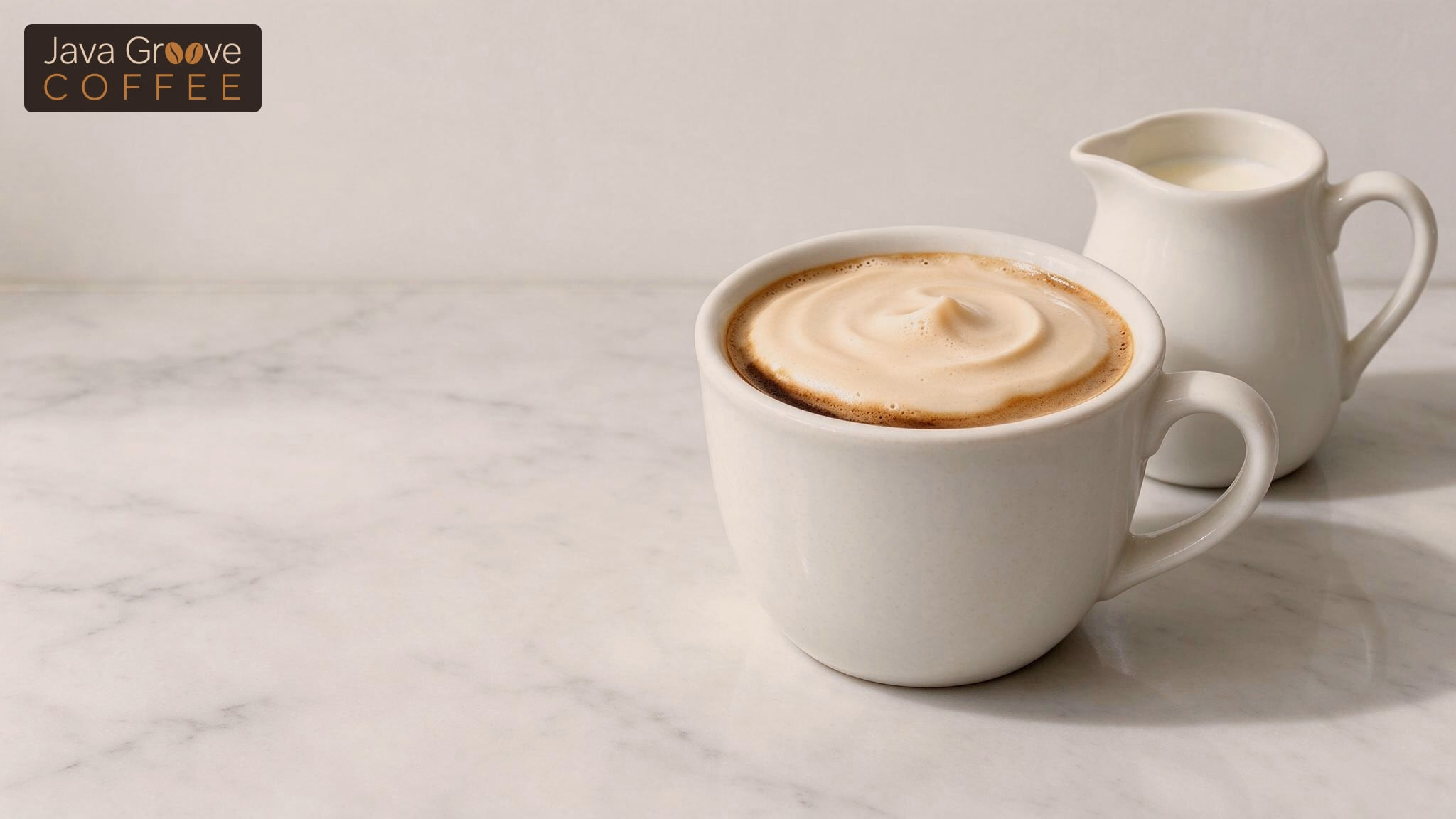 Breve coffee with creamy half-and-half foam next to a small milk pitcher